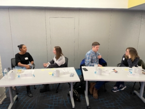 SLM board members sit facing each other in a 1 on 1 activity in front of a gray wall.